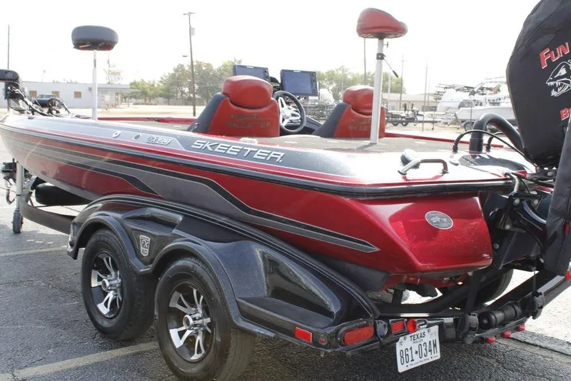 Slide: The Image of 2016 Skeeter FX20 bass boat, red and black, parked on a trailer in a lot. - 16