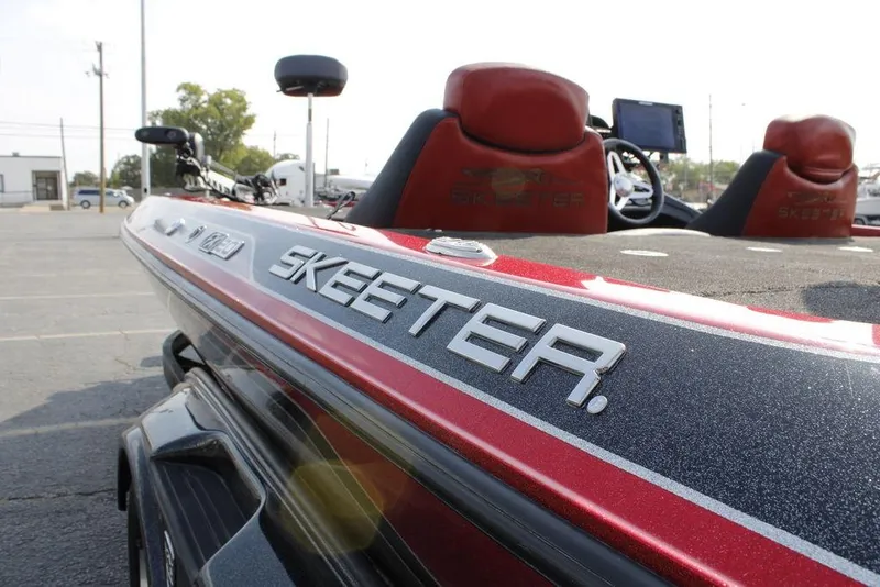 Slide: The Image of 2016 Skeeter FX20 boat with red and black detailing in a parking lot. - 33