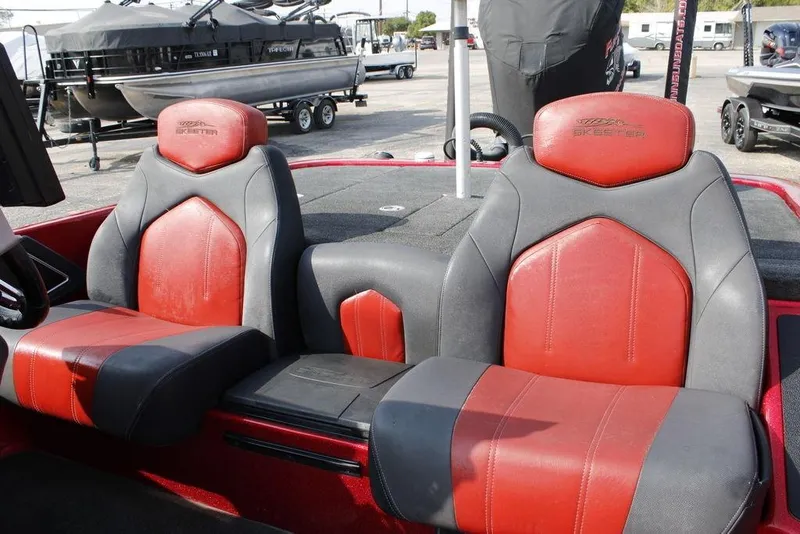 Slide: The Image of 2016 Skeeter FX20 boat seats, red and gray leather, in a marina setting. - 6
