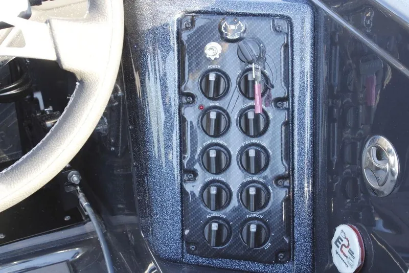 Slide: The Image of Control panel of 2026 Phoenix 921 ELITE boat with switches and steering wheel. - 14