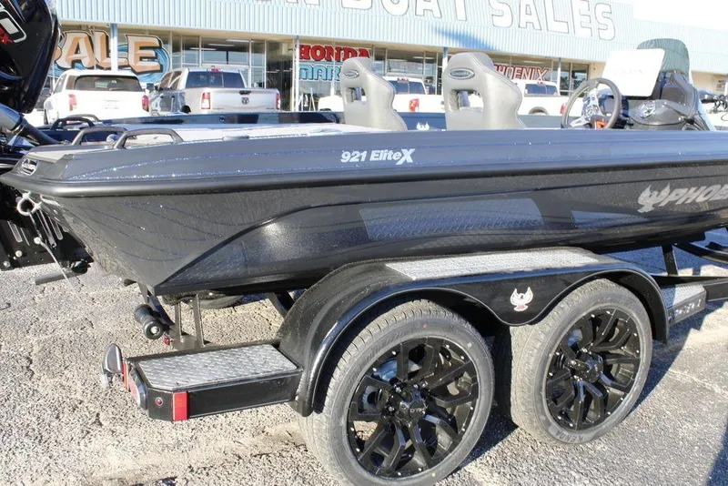 Slide: The Image of 2026 Phoenix 921 ELITE boat on trailer at dealership, showcasing sleek design and black wheels. - 7
