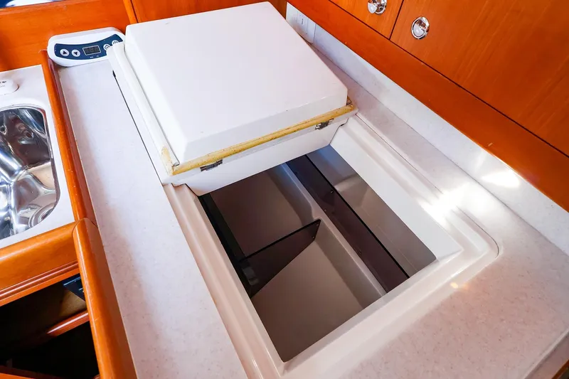 Slide: The Image of 2005 J Boats J/133 yacht galley with open storage compartment and wooden cabinetry. - 29