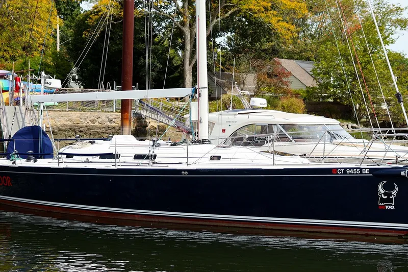 Slide: The Image of 2005 J Boats J/133 sailboat docked, surrounded by autumn trees and waterfront homes. - 37