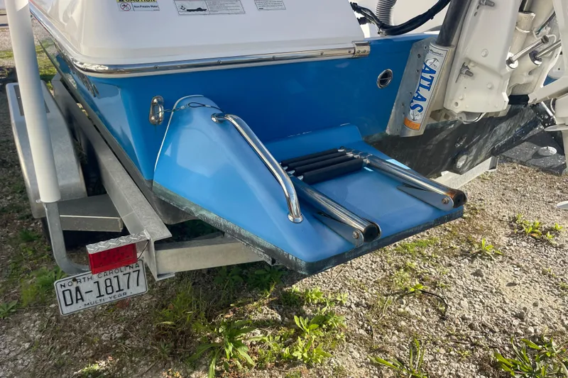 Slide: The Image of 2021 Everglades 243 Center Console boat on trailer, featuring a blue hull and swim ladder. - 24