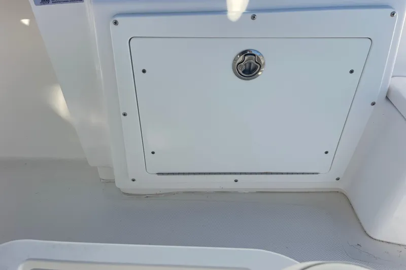 Slide: The Image of 2021 Everglades 243 Center Console storage compartment with secure latch on white deck. - 35