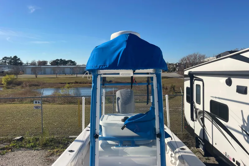 Slide: The Image of 2021 Everglades 243 Center Console boat with blue canopy, parked near a fence and RV. - 44