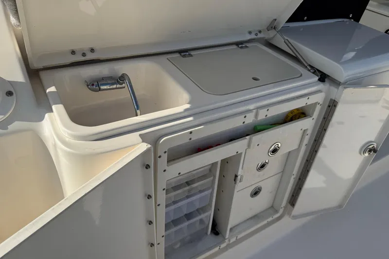 Slide: The Image of 2011 Pursuit OS 375 Offshore boat kitchen with sink and storage compartments. - 16