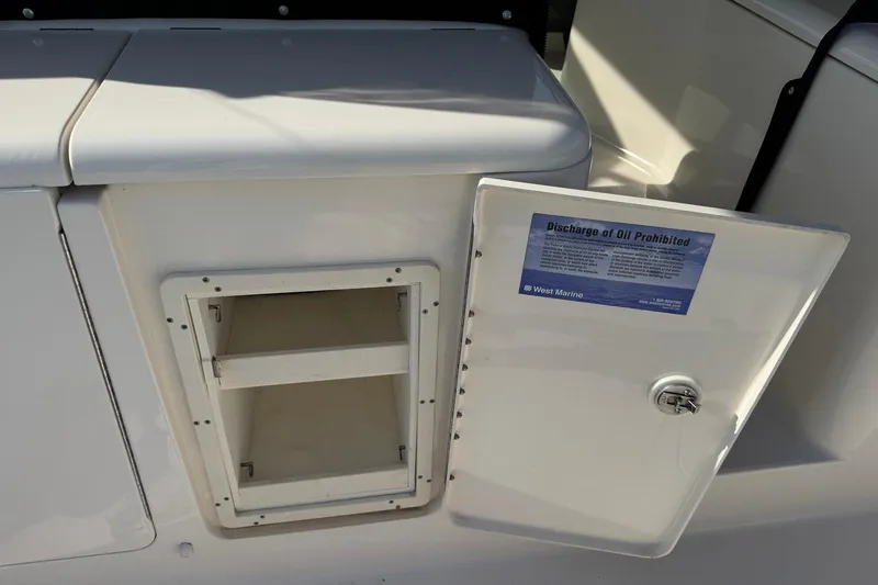Slide: The Image of 2011 Pursuit OS 375 Offshore boat storage compartment with open door and oil discharge warning. - 17