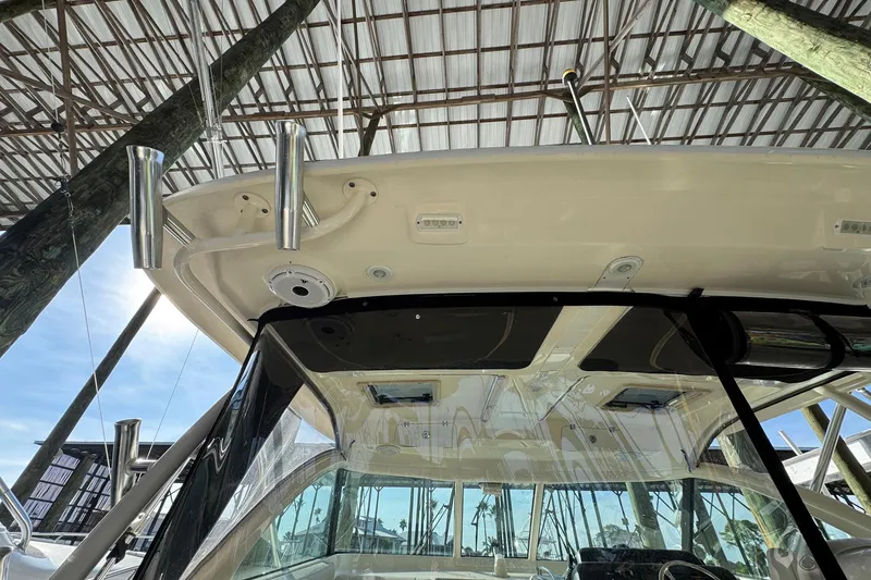 Slide: The Image of 2011 Pursuit OS 375 Offshore boat under a covered dock, showcasing its roof and rod holders. - 20