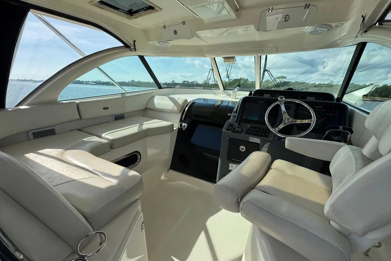 Slide: The Image of 2011 Pursuit OS 375 Offshore boat interior with helm and seating, overlooking water. - 23