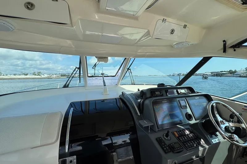 Slide: The Image of 2011 Pursuit OS 375 Offshore boat cockpit with navigation screens and steering wheel. - 24