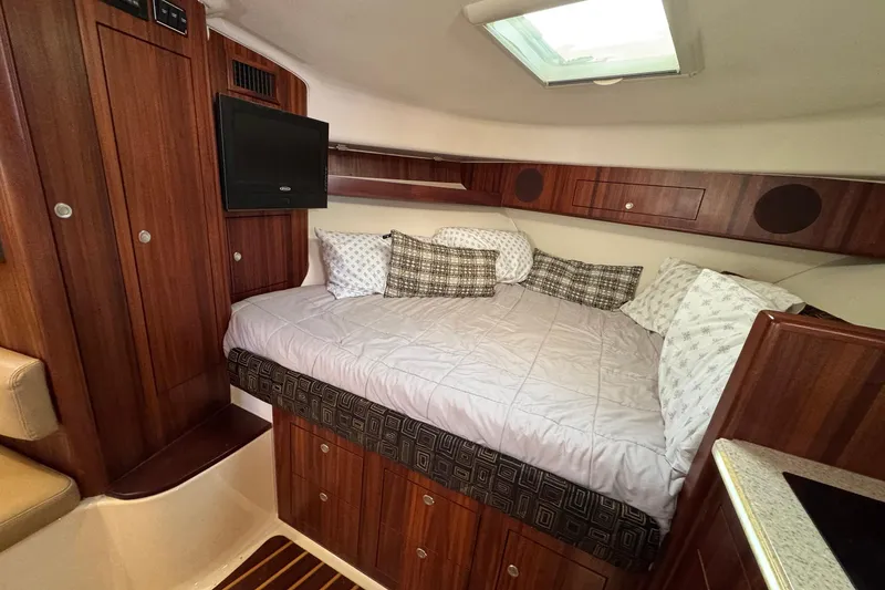 Slide: The Image of 2011 Pursuit OS 375 Offshore cabin with cozy bed and wooden interior. - 28