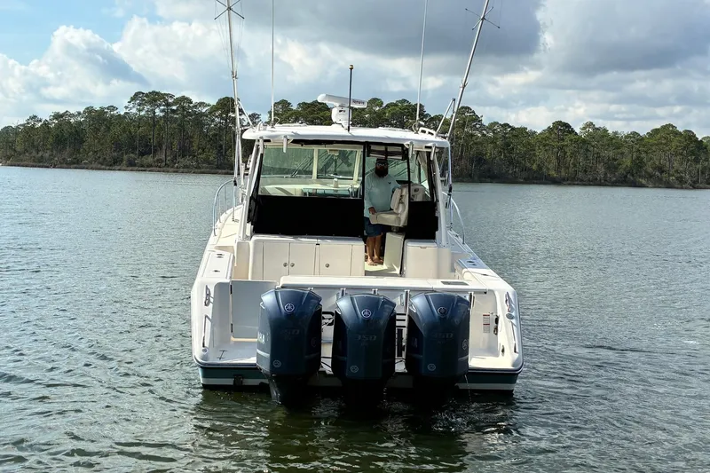 Slide: The Image of 2011 Pursuit OS 375 Offshore boat with triple outboard engines on a calm lake. - 6