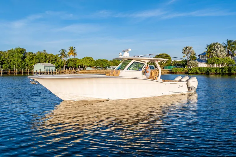Slide: The Image of 2020 Scout 355 LXF boat cruising on a sunny day, surrounded by lush greenery. - 10