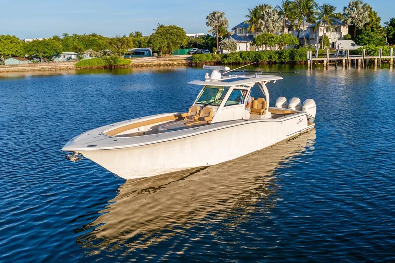 Slide: The Image of 2020 Scout 355 LXF boat on calm water, surrounded by lush greenery and waterfront homes. - 11