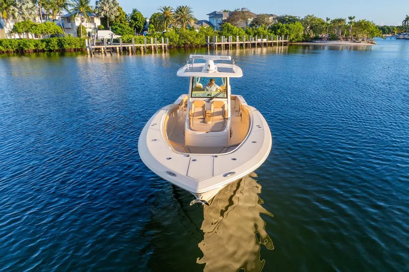 Slide: The Image of 2020 Scout 355 LXF boat cruising on a serene waterway with lush greenery. - 12