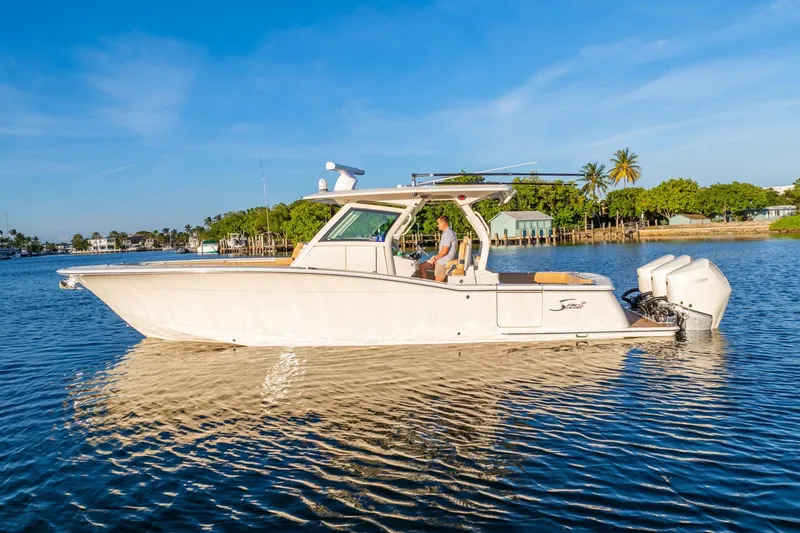 Slide: The Image of 2020 Scout 355 LXF boat cruising on a sunny day near a tropical shoreline. - 14