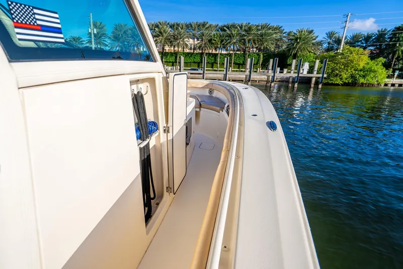 Slide: The Image of 2020 Scout 355 LXF boat docked by palm trees and clear blue water. - 33