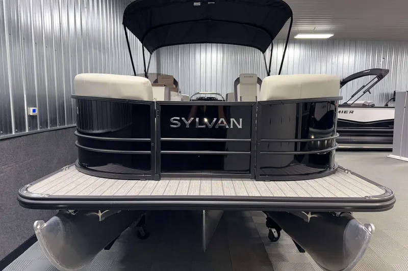 Slide: The Image of 2026 Sylvan Mirage X1 pontoon boat in showroom, rear view with canopy. - 18
