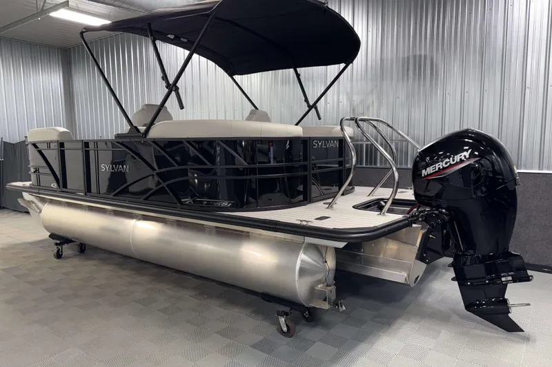 Slide: The Image of 2026 Sylvan Mirage X1 pontoon boat with Mercury outboard motor in a showroom. - 23