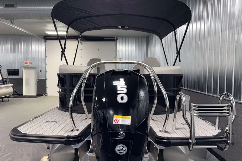 Slide: The Image of 2026 Sylvan Mirage X1 pontoon boat with 150 horsepower engine in a metal-walled showroom. - 24