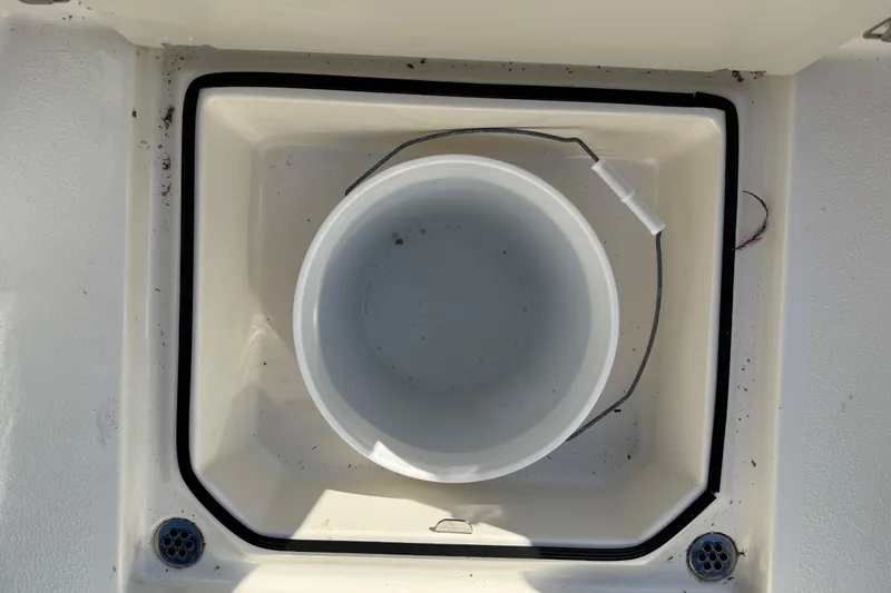Slide: The Image of 2019 Stingray 236 CC boat storage compartment with a white bucket inside. - 25