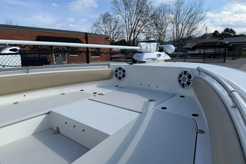 Slide: The Image of 2019 Stingray 236 CC boat deck with speakers and trolling motor, parked outdoors. - 37