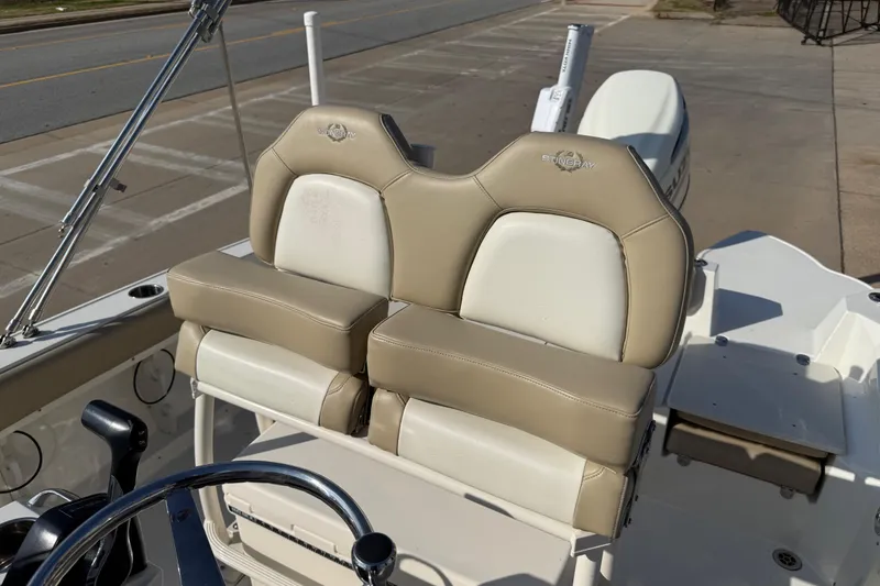 Slide: The Image of 2019 Stingray 236 CC boat with beige and white seating, docked on a sunny day. - 5