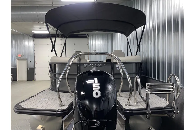 Slide: The Image of 2026 Sylvan Mirage X1 pontoon boat with 150 HP engine in a metal-walled showroom. - 16