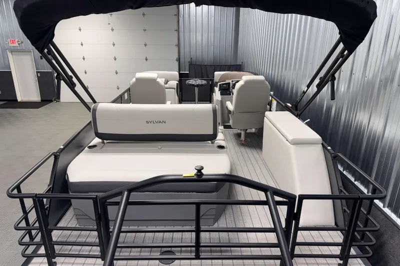 Slide: The Image of 2026 Sylvan Mirage X1 pontoon boat interior with seating and canopy in a showroom. - 16