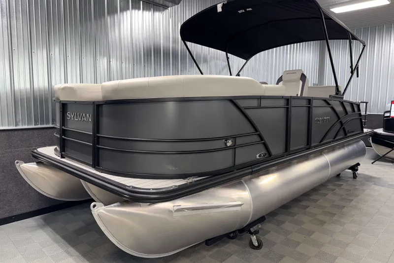 Slide: The Image of 2026 Sylvan Mirage X1 pontoon boat in showroom with sleek design and canopy. - 17