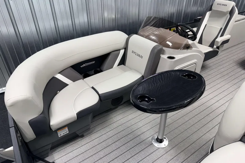 Slide: The Image of 2026 Sylvan Mirage X1 boat interior with plush seating and sleek table design. - 2