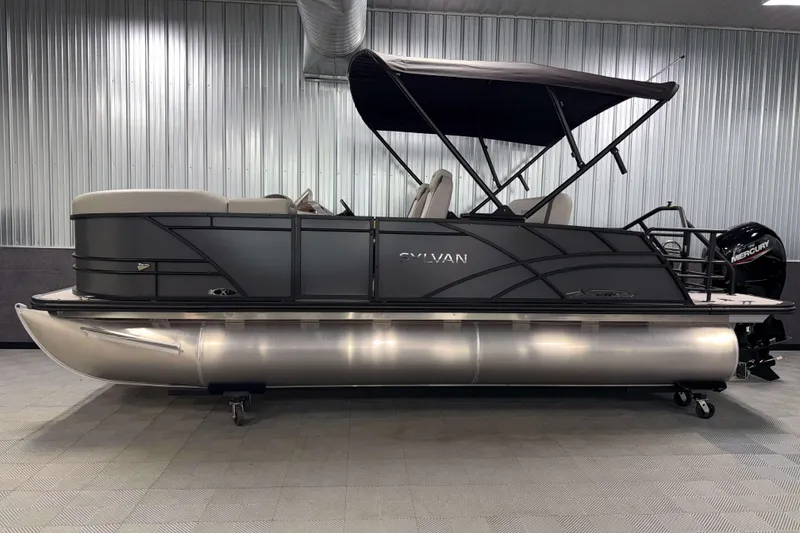 Slide: The Image of 2026 Sylvan Mirage X1 pontoon boat with canopy in a showroom setting. - 21