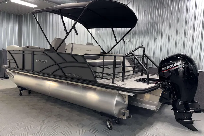 Slide: The Image of 2026 Sylvan Mirage X1 pontoon boat with Mercury outboard motor in a showroom. - 23