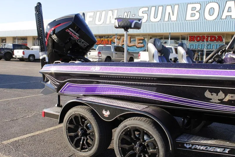 Slide: The Image of 2026 Phoenix 21 boat with purple detailing parked outside a boat dealership. - 3