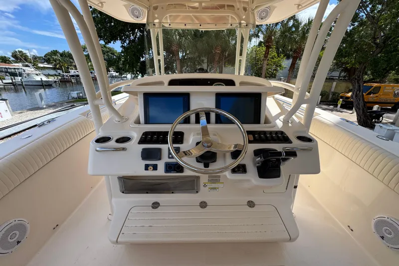 Slide: The Image of 2014 Grady-White Canyon 336 helm with dual screens and steering wheel, docked by water. - 15