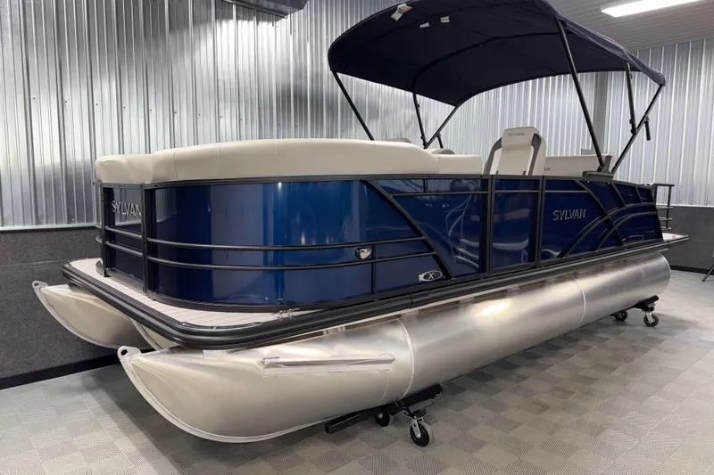 Slide: The Image of 2026 Sylvan MIRAGE X1 CLZ DH pontoon boat with blue exterior and canopy in showroom. - 16