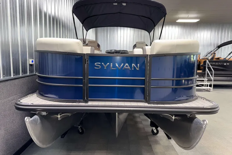 Slide: The Image of 2026 Sylvan MIRAGE X1 CLZ DH pontoon boat in showroom, blue exterior. - 17
