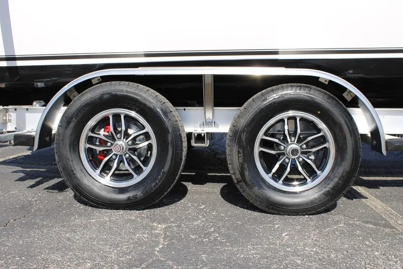 Slide: The Image of 2026 Tidewater 2110 Bay Max trailer wheels with chrome rims on asphalt. - 2