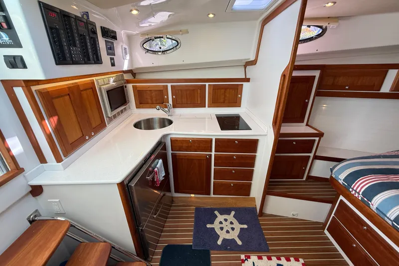 Slide: The Image of 2019 Back Cove Downeast 37 interior with wooden cabinetry, compact kitchen, and nautical decor. - 11