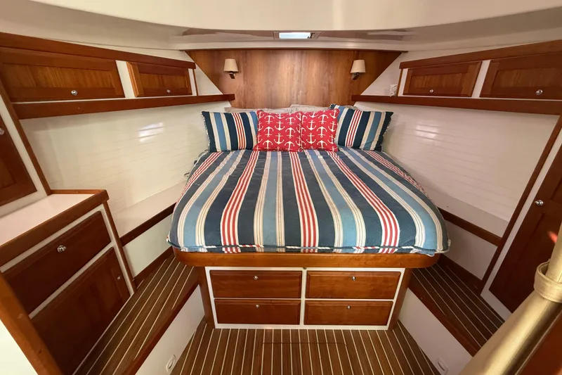 Slide: The Image of 2019 Back Cove Downeast 37 cabin with striped bedding and wooden cabinetry. - 12