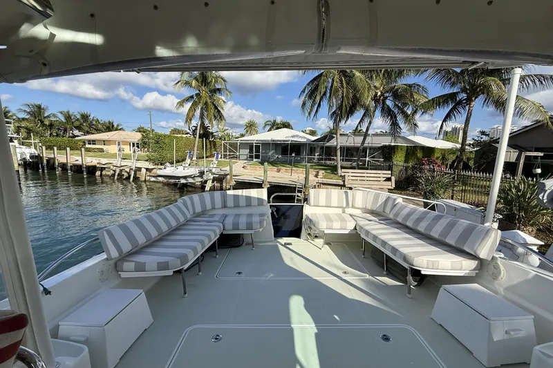 Slide: The Image of 2019 Back Cove Downeast 37 yacht with spacious deck and striped seating, docked by palm trees. - 2