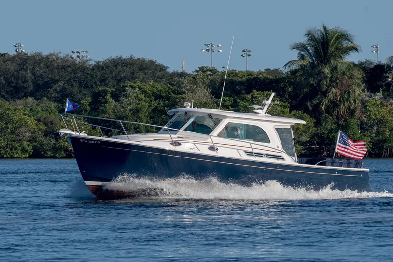 Slide: The Image of 2019 Back Cove Downeast 37 cruising on a scenic waterway with lush greenery. - 20