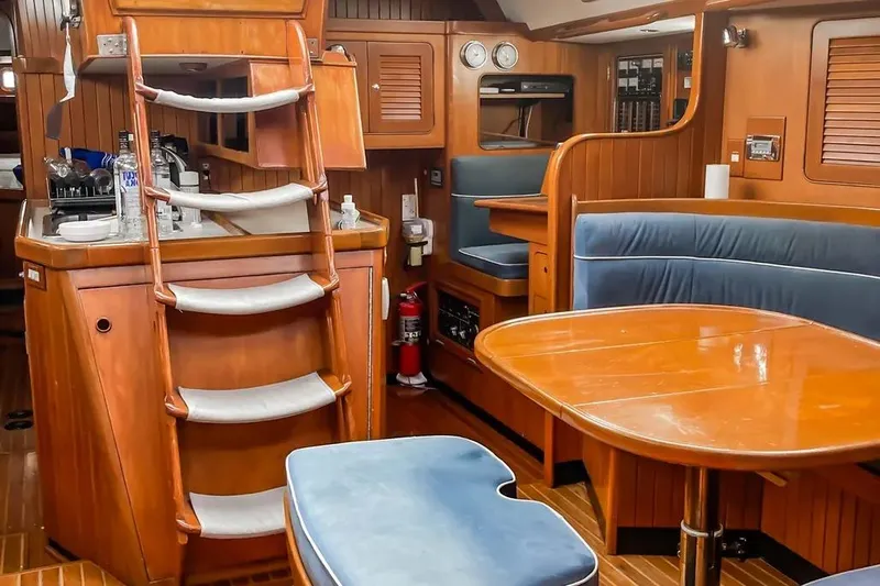 Slide: The Image of Interior of a 1999 Hylas 54 yacht with wooden finishes and blue seating. - 10