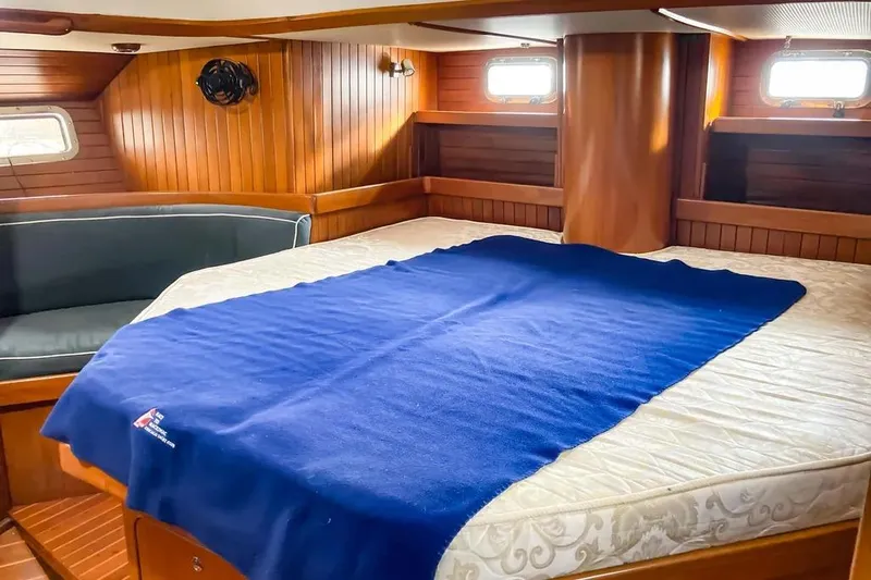 Slide: The Image of Cozy cabin interior of 1999 Hylas 54 yacht with wooden paneling and blue blanket. - 25