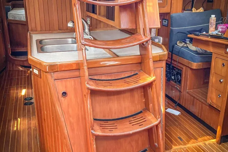Slide: The Image of Interior of 1999 Hylas 54 yacht with wooden ladder and compact kitchen area. - 9