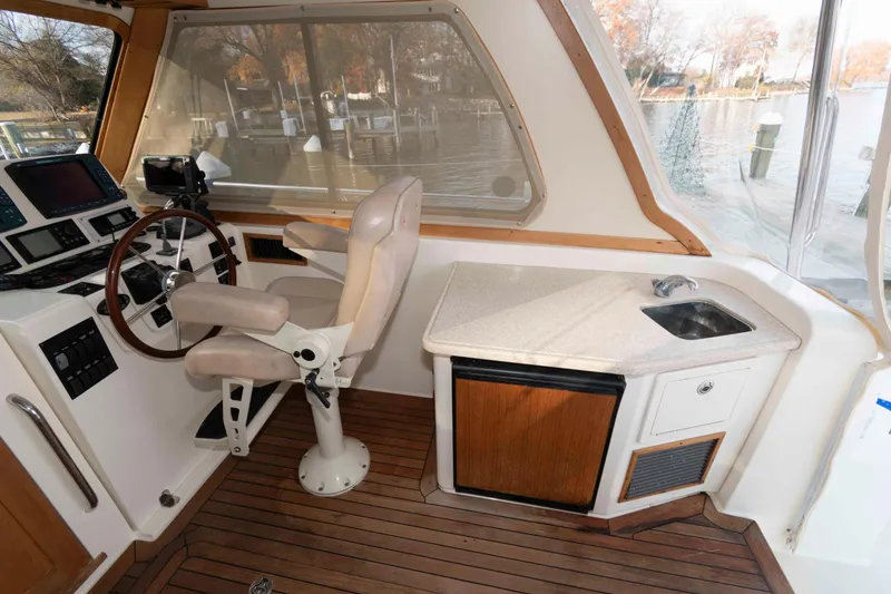 Slide: The Image of 2005 Sabre 38 Hardtop Express boat deck with striped seating, docked by calm water. - 17