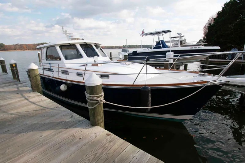 Slide: The Image of 2005 Sabre 38 Hardtop Express boat on calm water, surrounded by trees. - 2