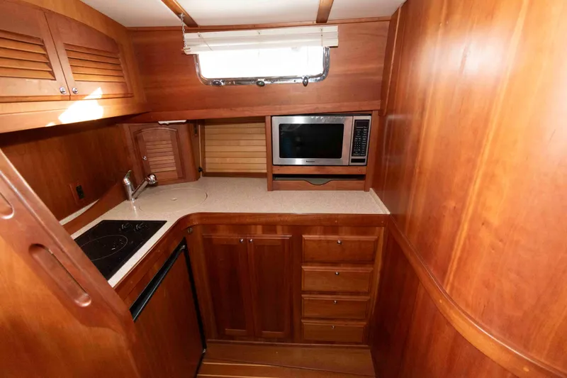 Slide: The Image of 2005 Sabre 38 Hardtop Express helm with steering wheel, navigation controls, and compact kitchenette. - 22