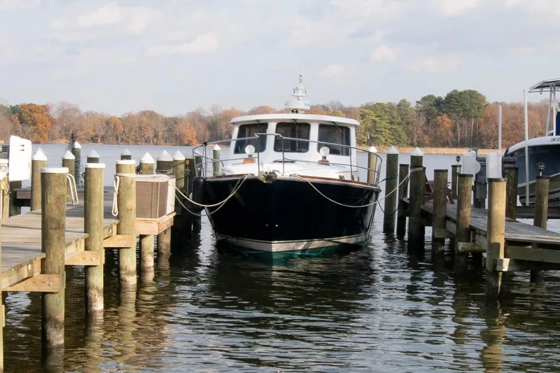 Slide: The Image of 2005 Sabre 38 Hardtop Express yacht on calm water, near a shoreline with trees. - 3